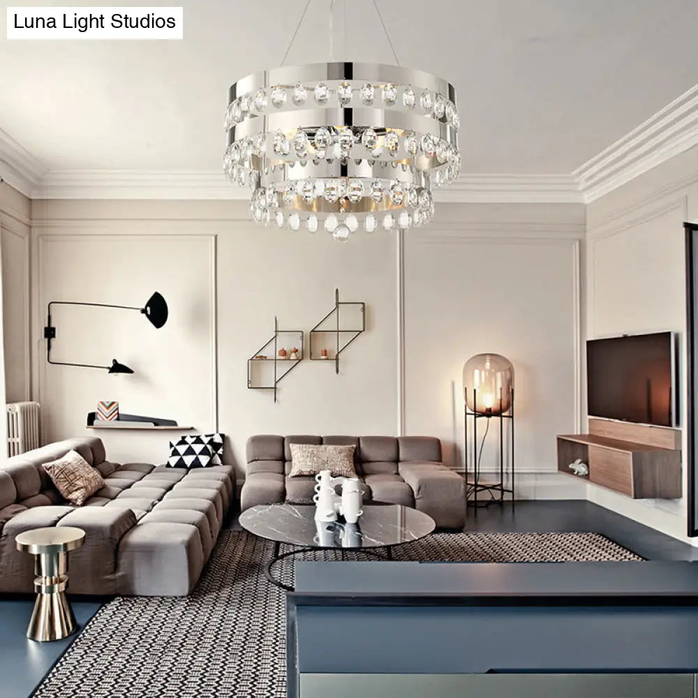 Lámpara de araña metálica multicolor con múltiples luces, decoración de cristal transparente y diseño de anillos escalonados en cromo.