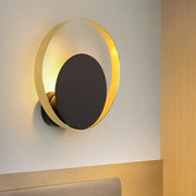 Mid century black and gold circle sconce featuring a modern gold-toned circular design with a matte black central disc