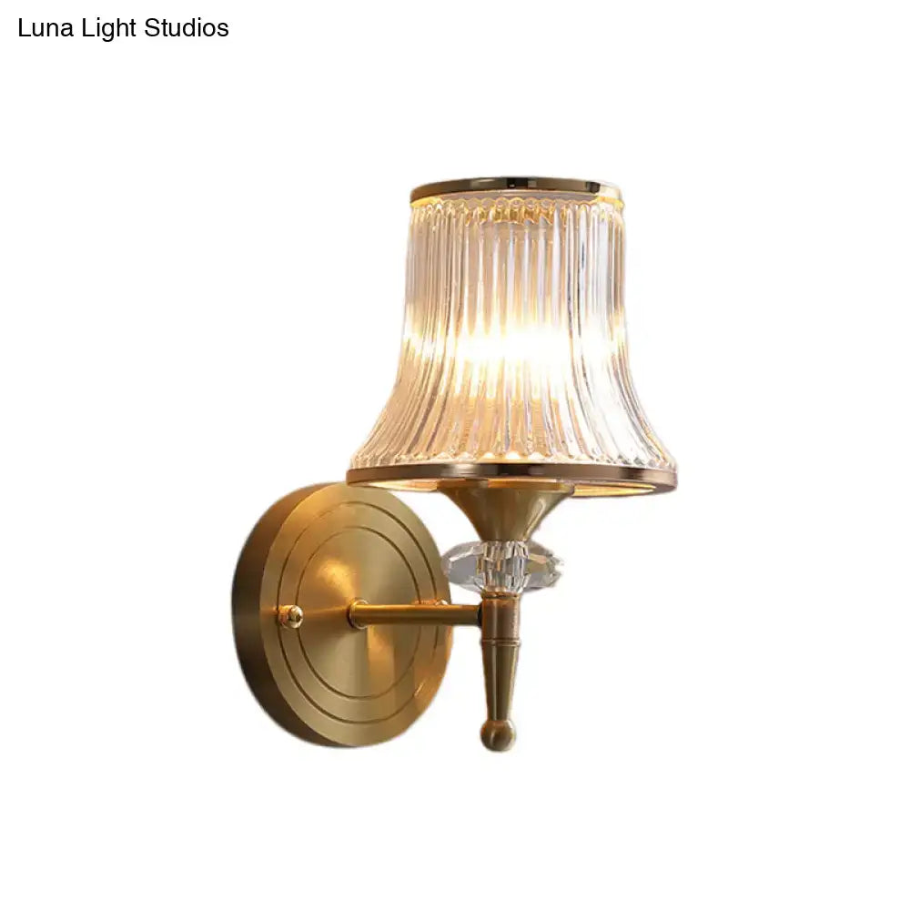Gold-toned mid-century brass wall mounted lamp with crystal ribbed wall glass shade for living room use