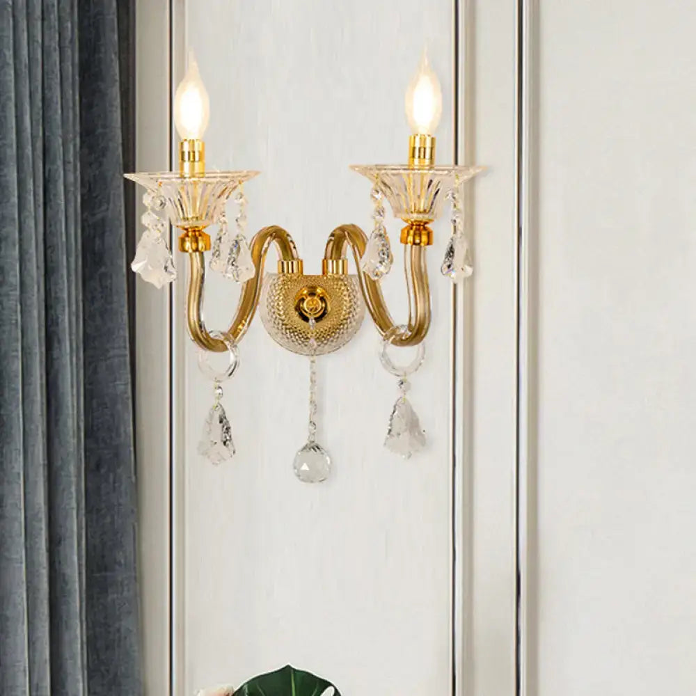 Mid-century brass wall mounted sconce with gold-toned crystal shade, two candle-style bulbs, and clear glass teardrop accents