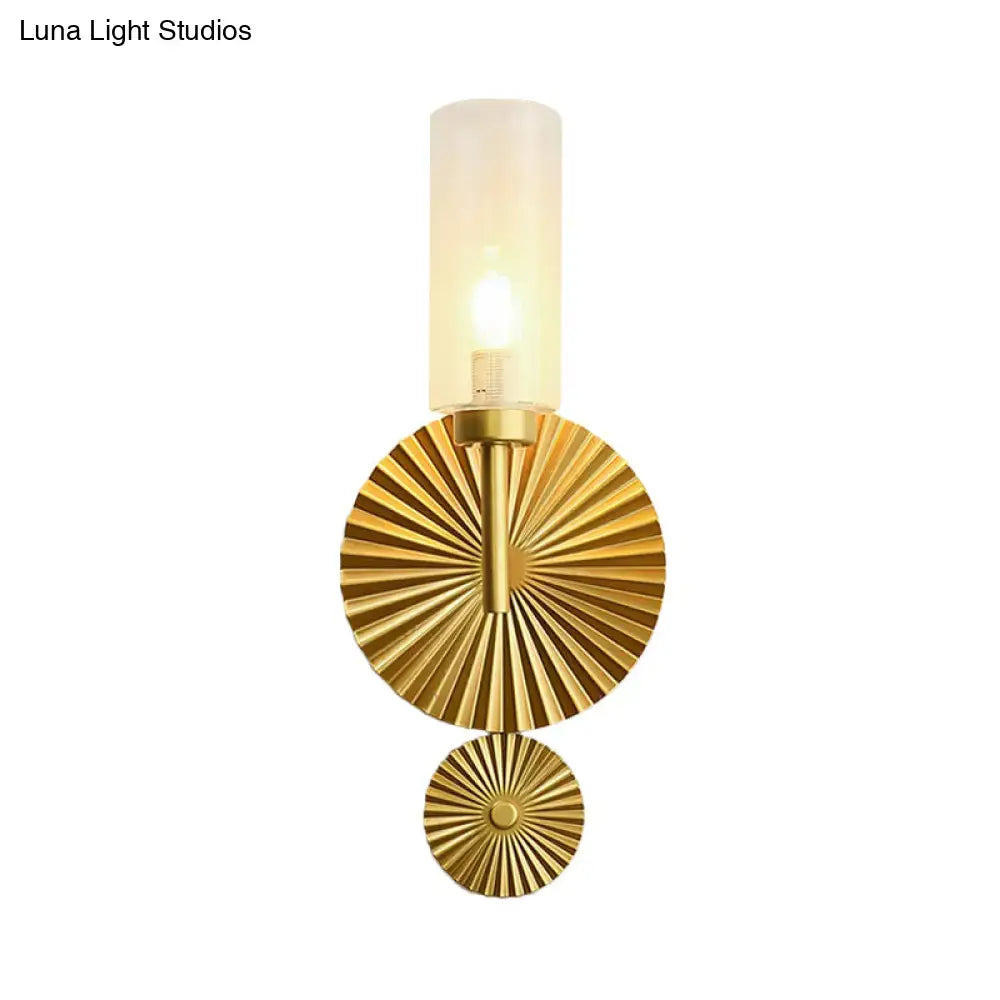 Gold-toned mid century wall sconce with scalloped brass backplate and cylindrical frosted glass shade for bedrooms