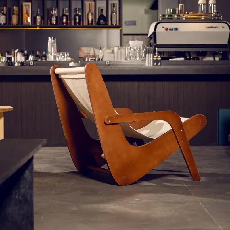 A mid-century modern decorbites canvas recliner with a warm brown wooden frame and cream fabric sling for living rooms