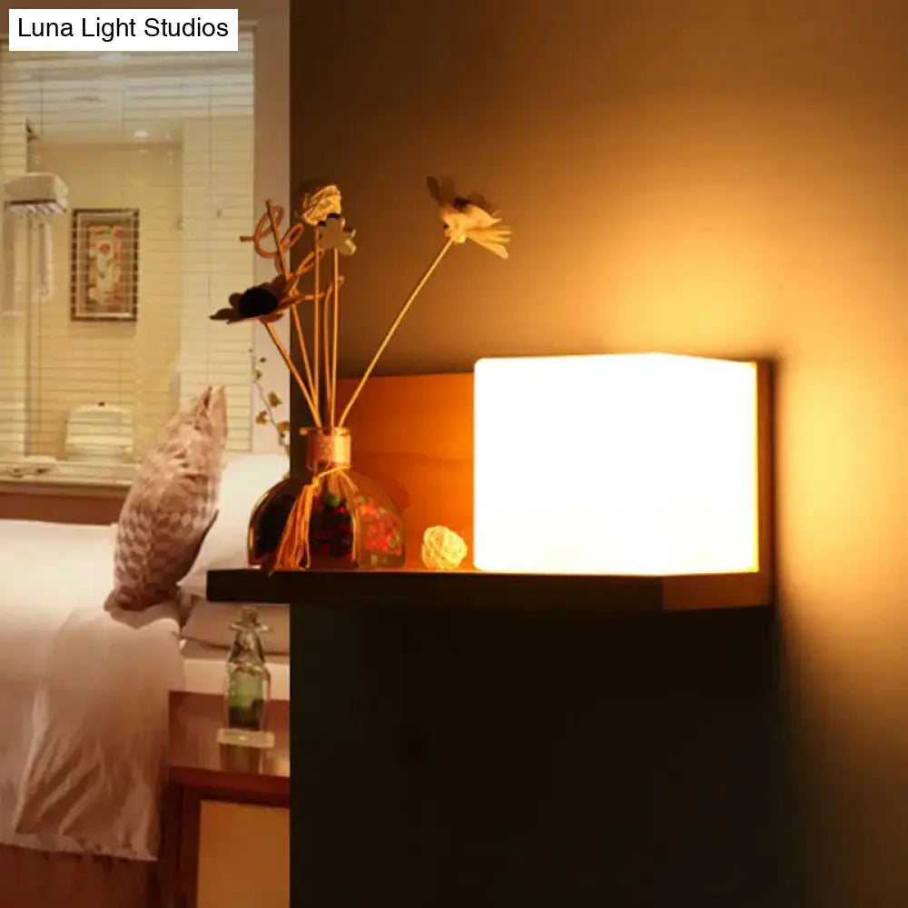 Warm white rectangular wall light with a milk glass cube and sleek black frame for bedroom sconce with wood shelf