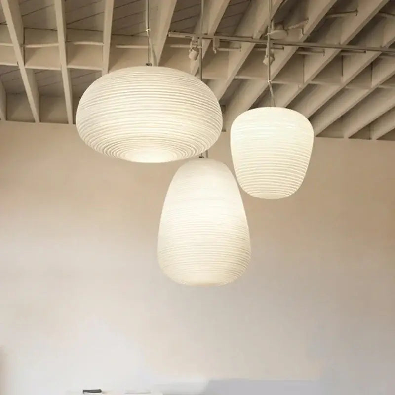 Three off-white ribbed paper lanterns resembling glass whorls cocoon pendant light for dining room use