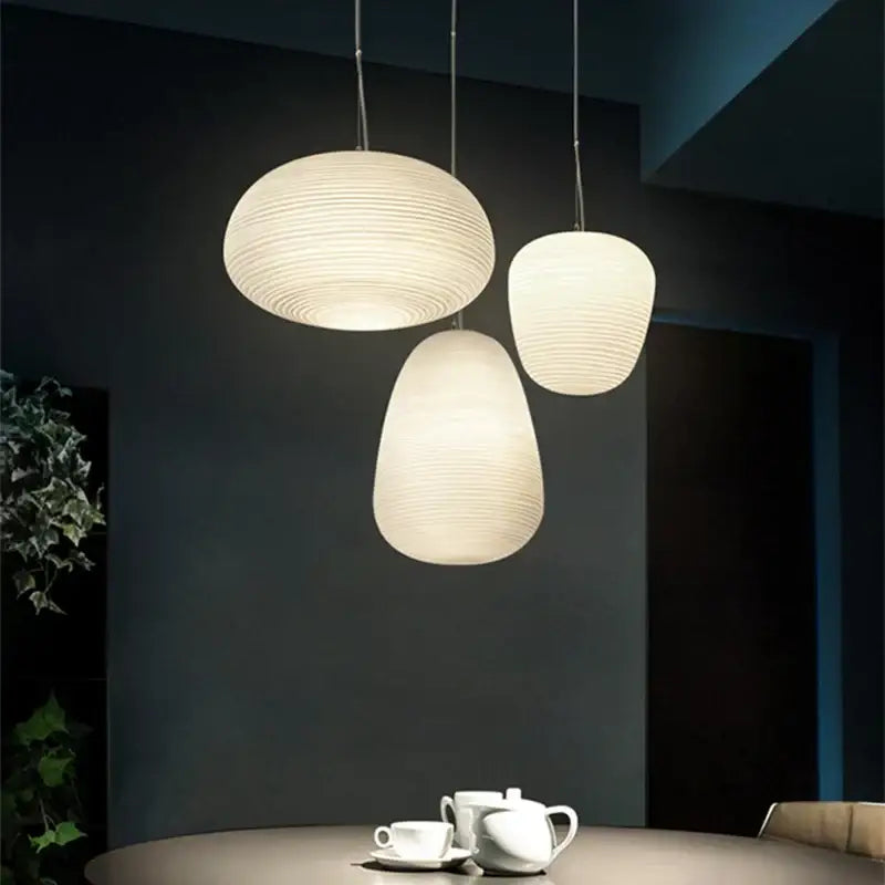 Three elegant milky white glass whorls cocoon pendant lights with subtle ridges for dining room use