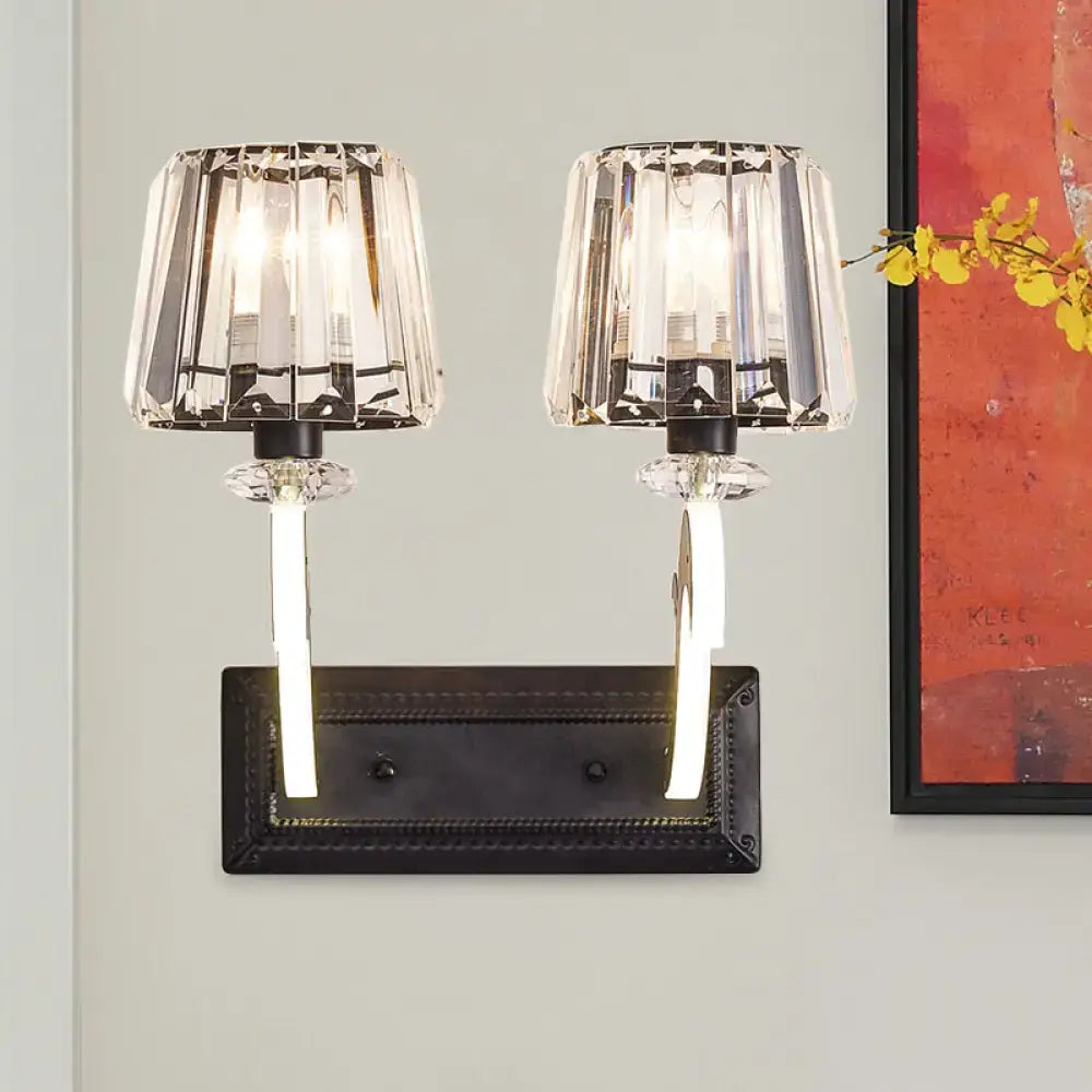 Minimal brass and crystal wall lamp with crystal-encased dual lights, black base, beaded trim, and cone shade for bedroom