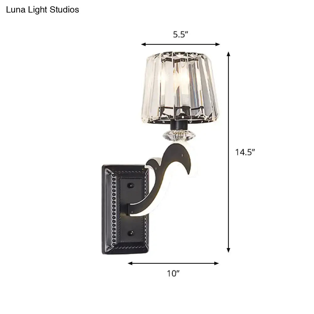 A sleek black wrought iron wall lamp with a faceted crystal cone shade for minimal bedroom lighting