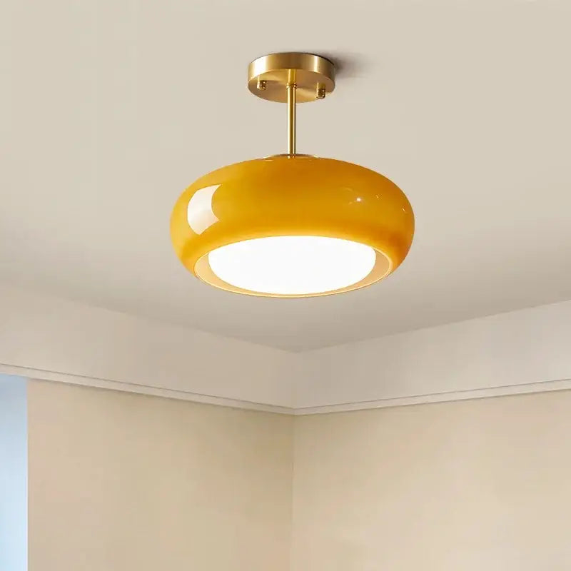A sleek minimalist amber glass copper led ceiling light with a mustard-yellow dome and brass fixture for hallway