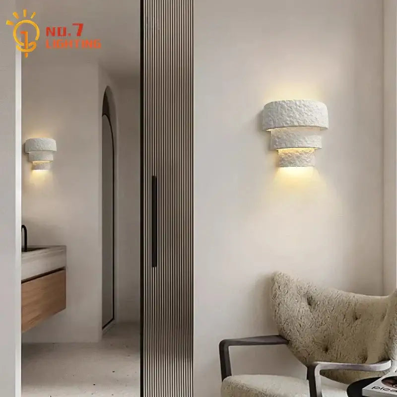 Minimalist bauhaus white gypsum wall lamp with textured layered design emitting warm light for bedroom use