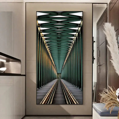 A framed vertical canvas print of green steel train tracks under a lattice ceiling paired with a minimalist beige led wall lamp