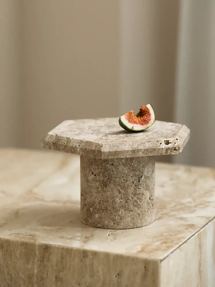 Minimalist hexagonal serving tray made of beige brown travertine with a rustic stone pedestal and cylindrical base