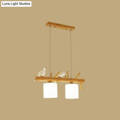 Minimalist beige drum island lighting with natural wood frame, white glass shades, and ceramic birds on wood branch design