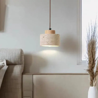 Minimalist pendant light with beige stone shade and natural wood top suspended by brown cord for kitchen dining room