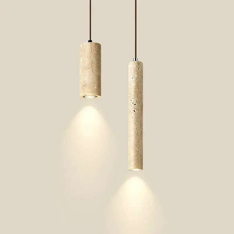 Two beige travertine cylindrical pendant lights with textured finish hang from black cords over dining table