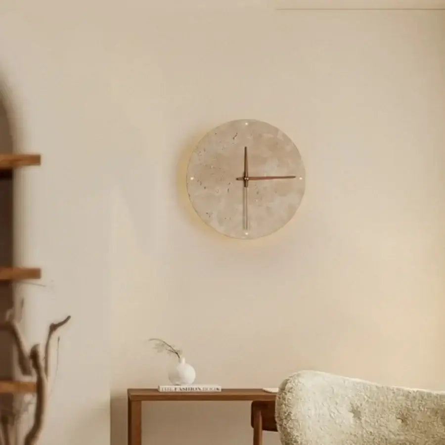 Minimalist beige travertine stone wall clock with textured face and slender metallic hands for led wall lights decor