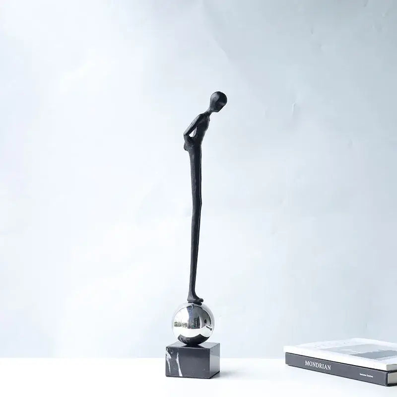 Black minimalist abstract thinker metal figurine standing on a reflective silver sphere for modern living room decorbites decor