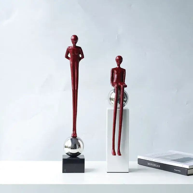 Two sleek glossy red metal figurines with elongated limbs as minimalist decorbites abstract thinker living room decor