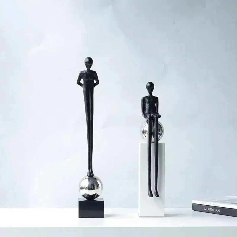 Two minimalist black metal figurines with elongated limbs on reflective spheres for abstract thinker decorbites living room decor