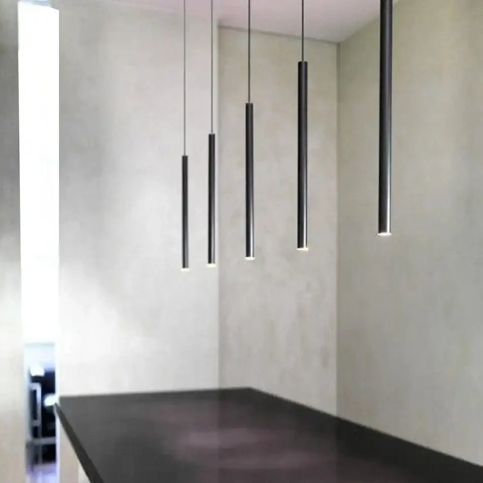 Five sleek black aluminum led ceiling track spotlights emit a soft glow in a minimalist kitchen setting