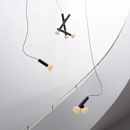 Minimalist black and white glass pendant lights with cylindrical black shades and off-white bulbs for dining room use