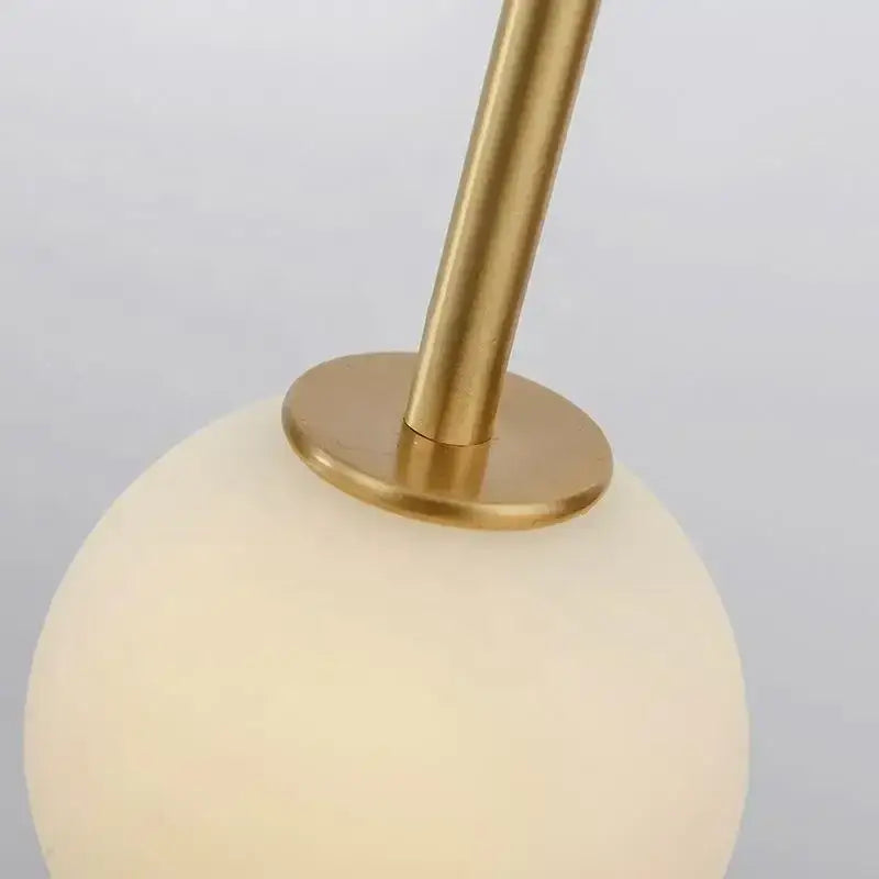 Minimalist black bronze glass ball pendant light with gold-toned metal stem and frosted opal glass globe for living room decor