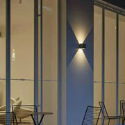 Minimalist black cement led wall lamp with two angled lights casting a warm glow for living room use