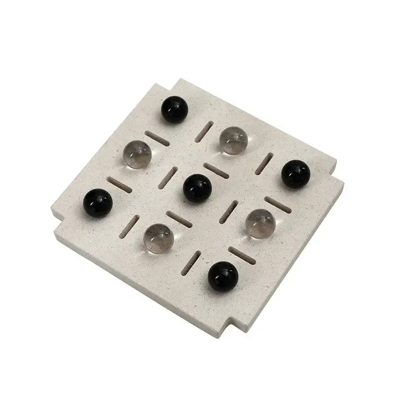 Minimalist black and clear geometric glass bead chess set with light gray stone board and alternating black and translucent marbles