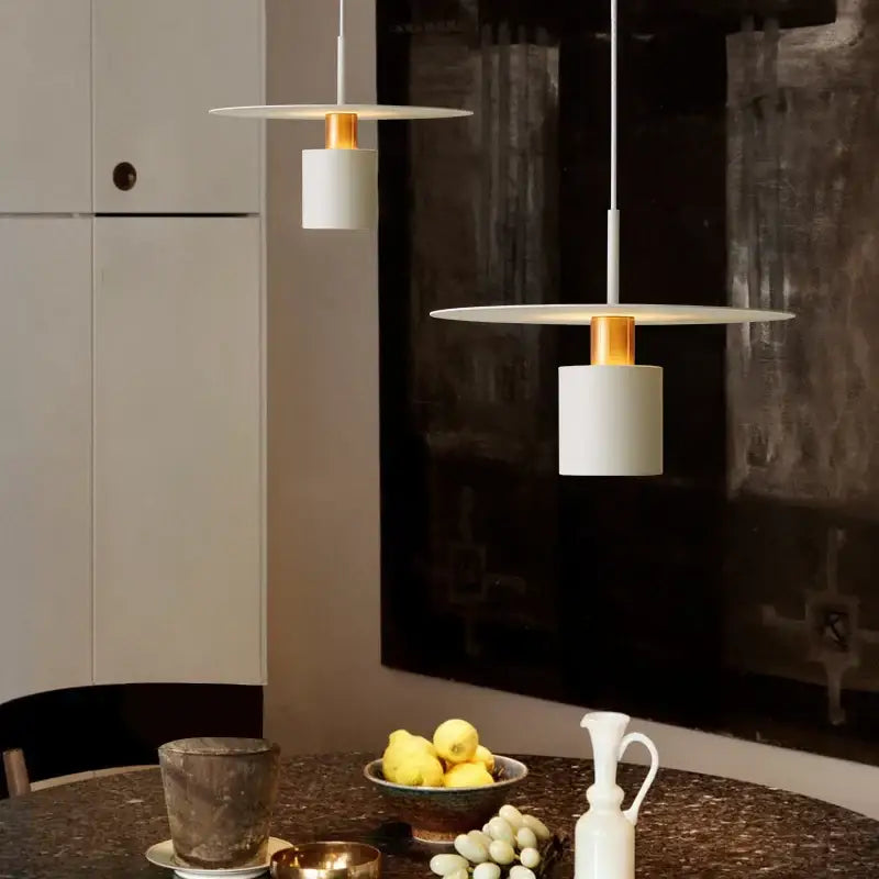 Modern white pendant lights with gold accents hang above a dining table in decorbites iron art led chandelier style