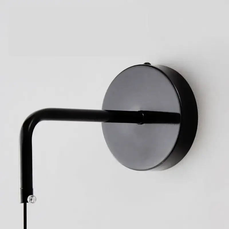 Minimalist black copper wall lamp with matte finish curved arm and circular base for sleek bedroom decorbites copper wall light