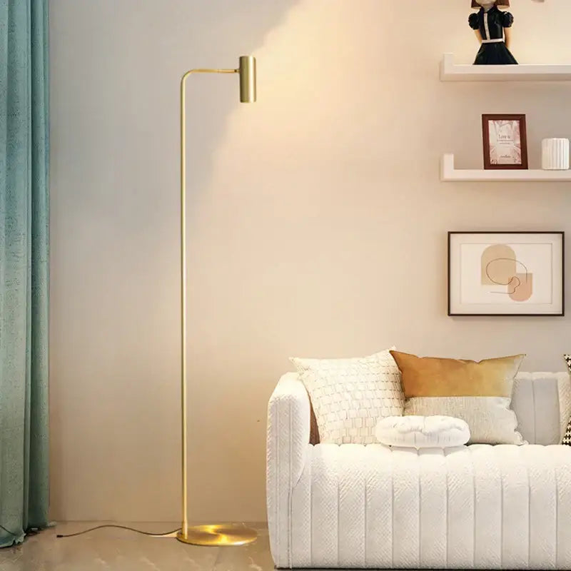 A sleek gold-finished decorbites brass floor light with a minimalist curved arm ideal for bedroom decor