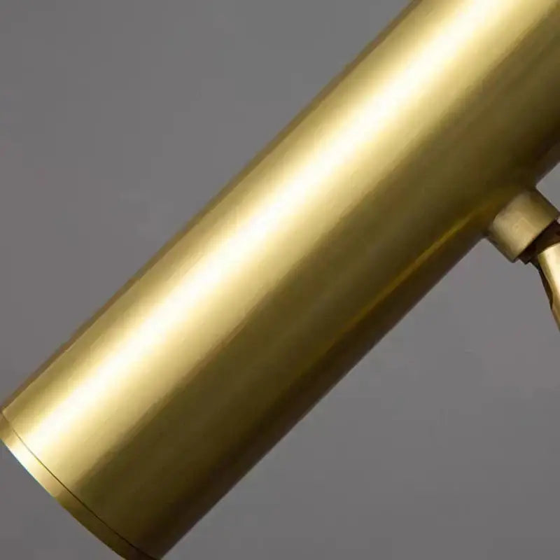 A sleek brushed brass cylindrical base of the minimalist decorbites brass floor light with a smooth reflective surface