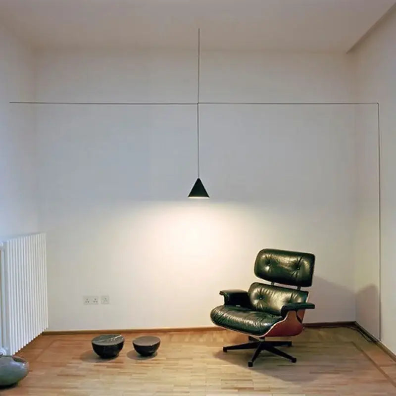 Dark green leather eames lounge chair with red wooden frame and black casters near decorbites geometric led pendant light