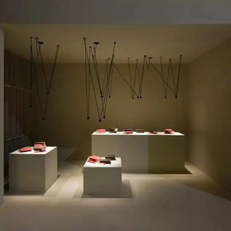 Minimalist black geometric pendant lamp displayed above white pedestals with neatly arranged red books for living room decorbites black geometric