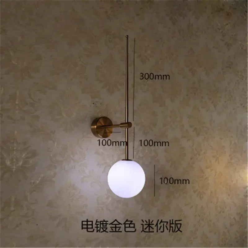 A minimalist black glass ball led wall lamp with brass-finished arm featuring a frosted glass globe for bedroom decorbites glass ball