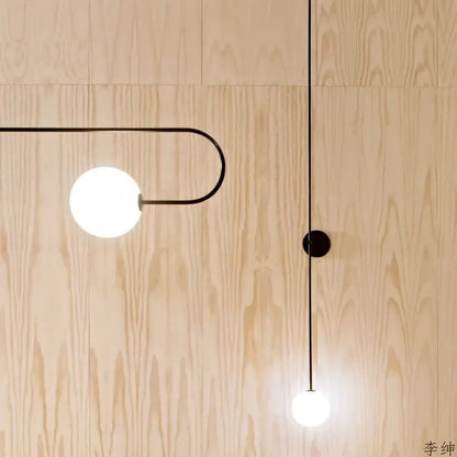 Minimalist black glass ball led wall light with spherical white glass shades against light wood decorbites wall light