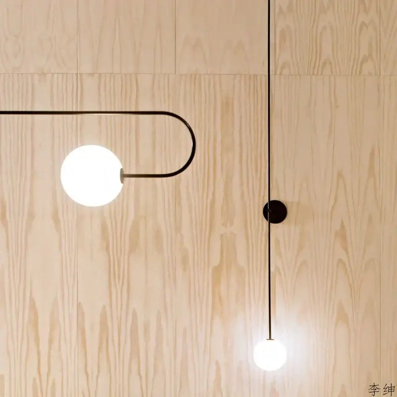 Minimalist black glass ball led wall light with spherical white glass shades against light wood decorbites wall light