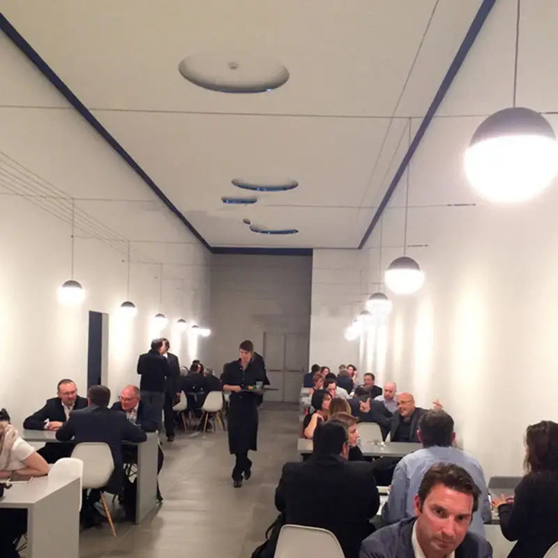 A modern minimalist restaurant interior featuring black decorbites glass ball pendant lights over a central aisle