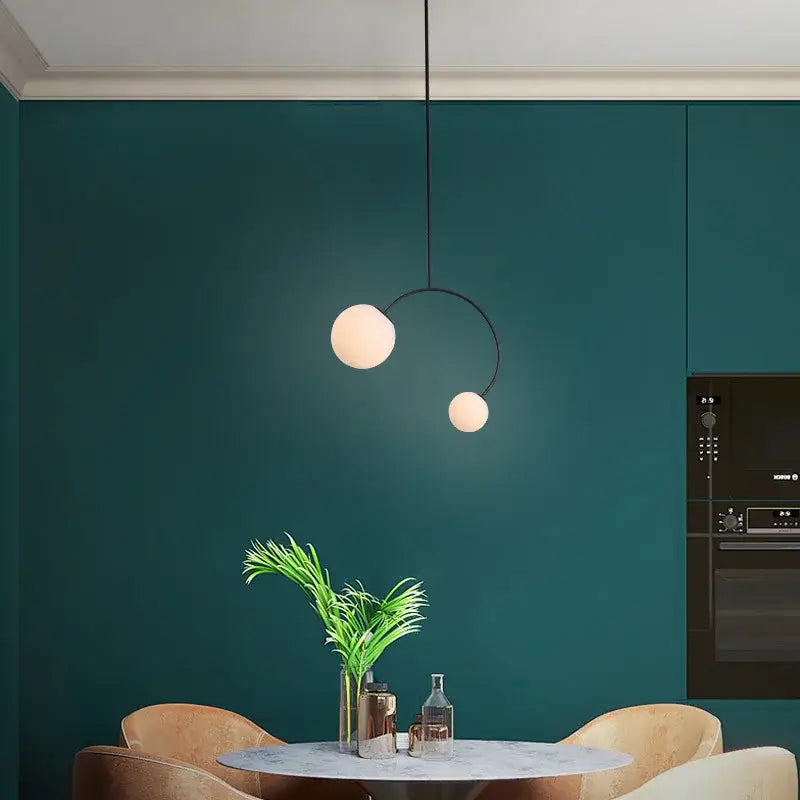 Minimalist black glass ball pendant lights with two frosted glass spheres on a curved arm for dining room decorbites