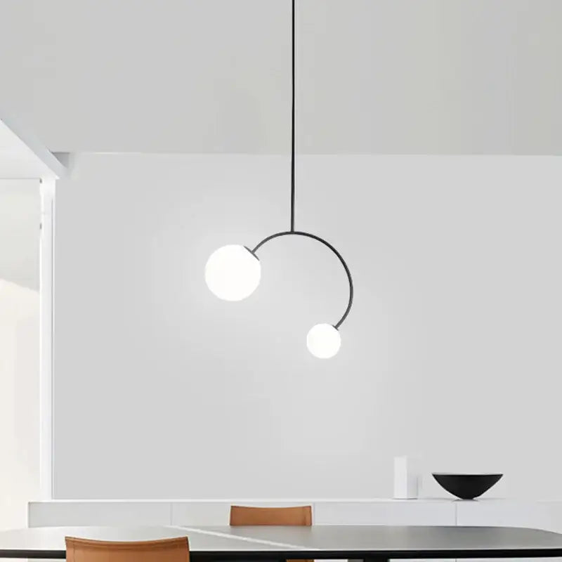 Minimalist black metal glass ball pendant lights with two frosted white bulbs on curved arm for dining room decorbites