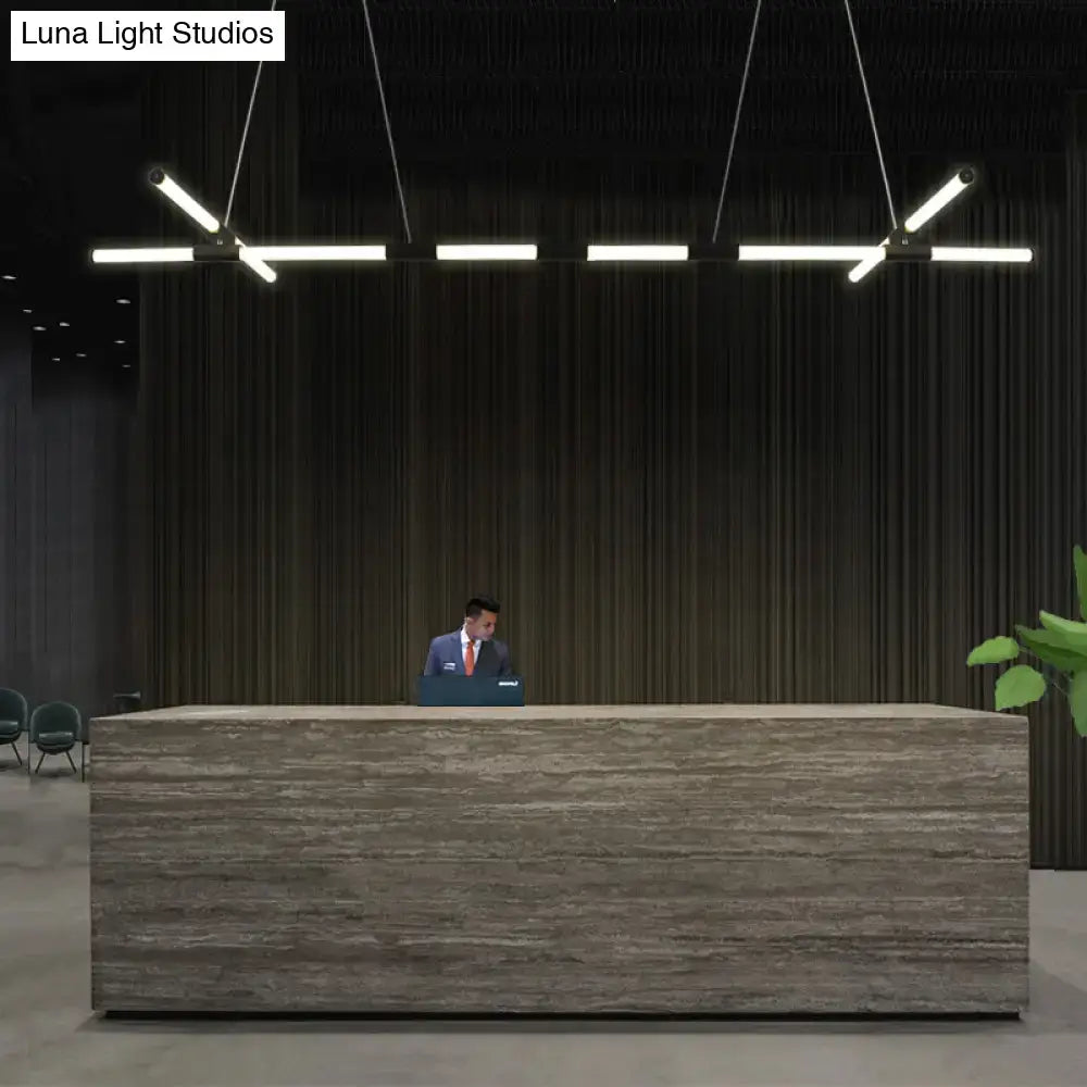 Modern reception desk with textured gray stone surface and black glass tube pendant lamps with frosted white shades above