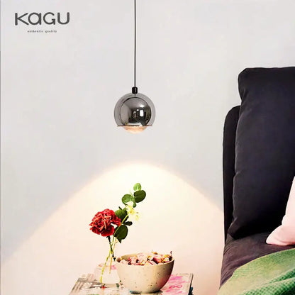 A sleek spherical chrome pendant light with minimalist design hangs from a thin black cord for bedroom and kitchen island decorbites gold metal luster