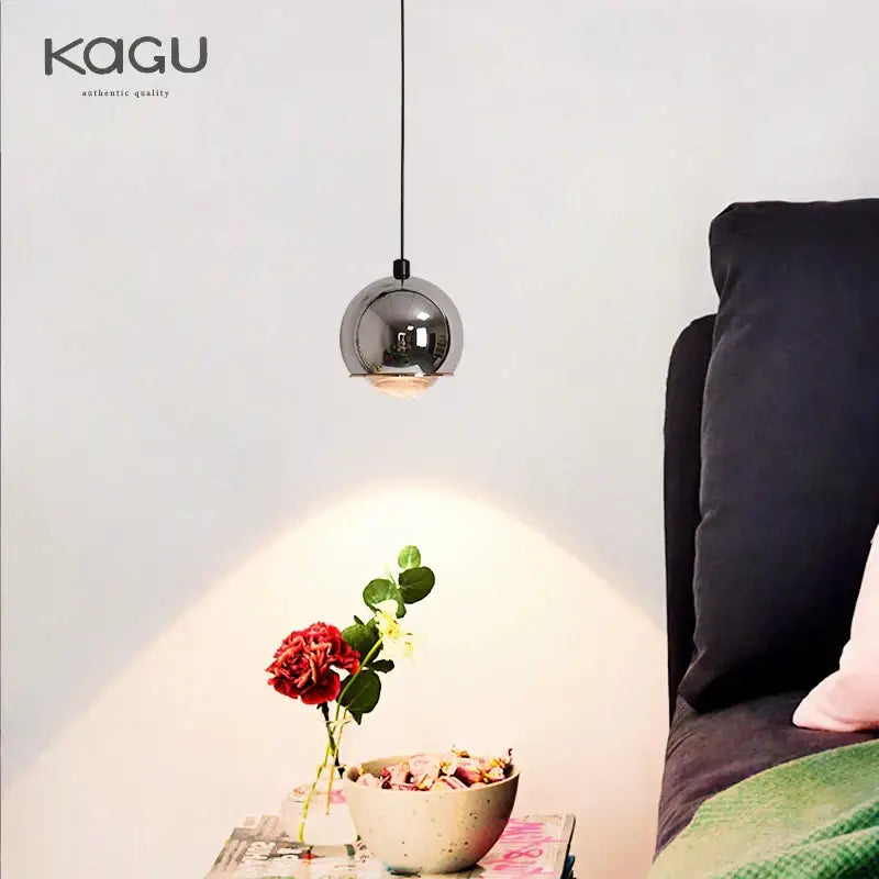 A sleek spherical chrome pendant light with minimalist design hangs from a thin black cord for bedroom and kitchen island decorbites gold metal luster