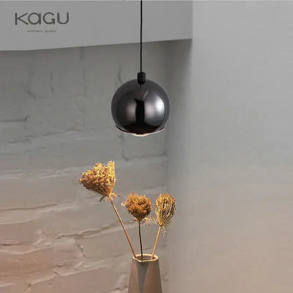 A sleek black glossy pendant light with minimalist design hangs from a thin cord for bedroom and kitchen island decorbites gold metal luster