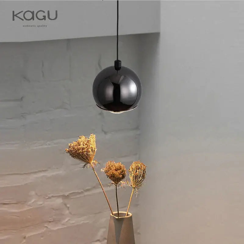A sleek black glossy pendant light with minimalist design hangs from a thin cord for bedroom and kitchen island decorbites gold metal luster