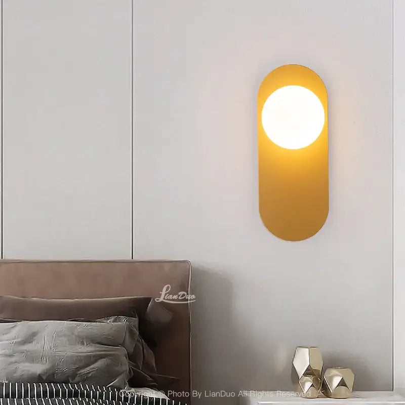 Minimalist black and gold glass ball led wall sconce with warm-toned oval matte gold finish and circular illuminated face