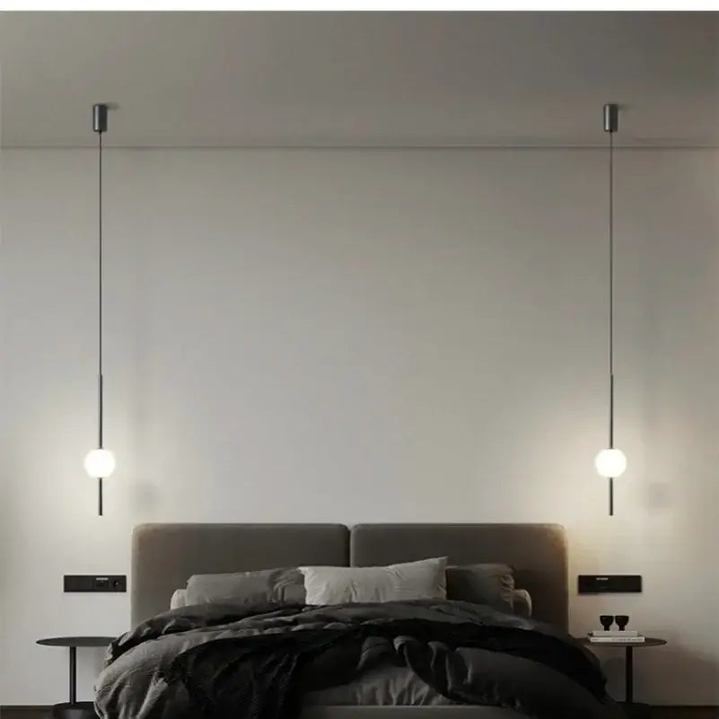 Minimalist black and gold globe pendant light with spherical glass bulbs and cord pendant installation above bed