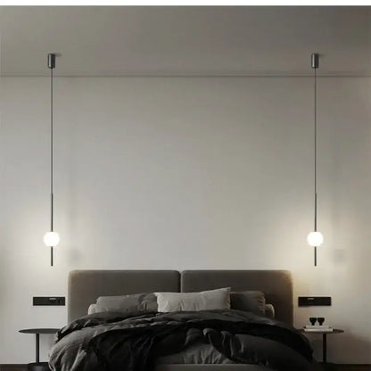 Minimalist black and gold globe pendant light with spherical glass bulbs and cord pendant installation above bed