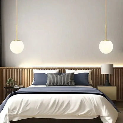 Minimalist black and gold globe pendant light with frosted glass shades and led bulb hanging above the bed