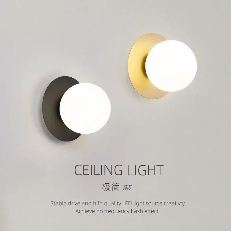 Two minimalist led wall lamps with frosted glass globes in matte black and brushed gold for living room use