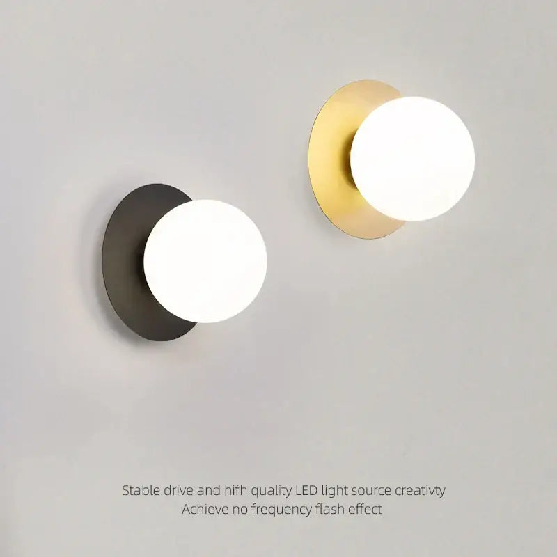 Minimalist black and gold led wall sconce with matte black and brushed gold circular bases and white glass globe shades